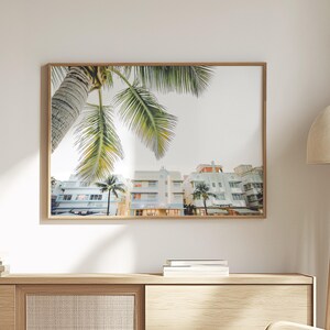 South Beach photography print showing 3 Art Deco hotels framed under a palm tree on the top left.  Soft pastel colors.