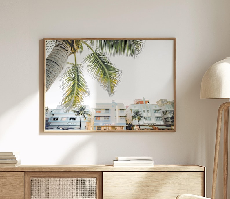 South Beach photography print showing 3 Art Deco hotels framed under a palm tree on the top left.  Soft pastel colors.