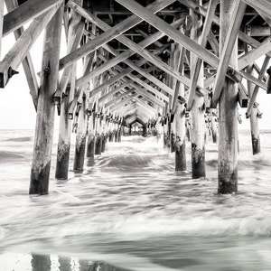 PHotography print of underneath a pier with small waves.  Black and white version.