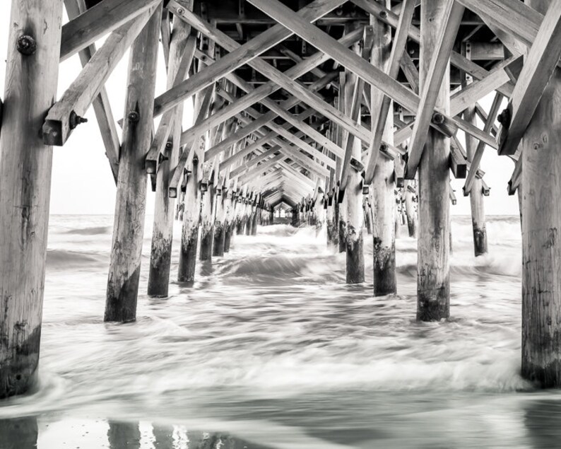 PHotography print of underneath a pier with small waves.  Black and white version.