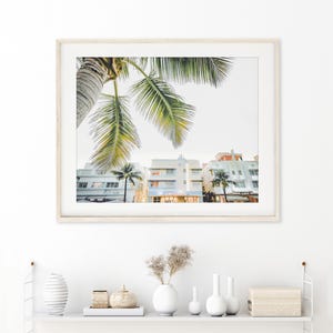 South Beach photography print showing 3 Art Deco hotels framed under a palm tree on the top left.  Soft pastel colors.