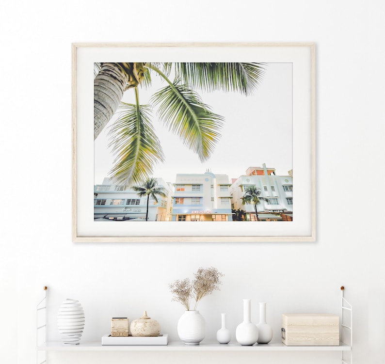 South Beach photography print showing 3 Art Deco hotels framed under a palm tree on the top left.  Soft pastel colors.