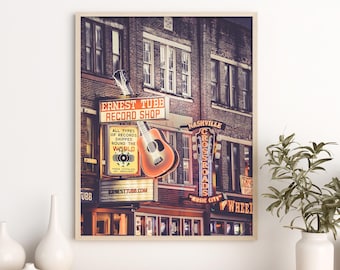 Op de afbeelding: Een vintage foto van Ernest Tubb Record Shop in Nashville, Tennessee. Het neonbord van de winkel is verlicht en een gitaar hangt boven het bord. Het bord luidt "Ernest Tubb Record Shop" en "Alle soorten platen worden wereldwijd verzonden".