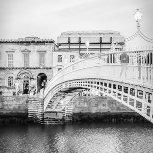 Photography print of Ha'penny Bridge in Dublin Ireland.  Shows water underneath with Merchant's bar in background.  Black and white version.