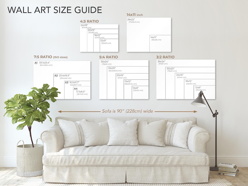 May include: A wall art size guide with different ratios and sizes for wall art. The guide shows the dimensions in inches and centimetres. The guide is displayed above a white sofa with cushions. The sofa is 90 inches (228 cm) wide.