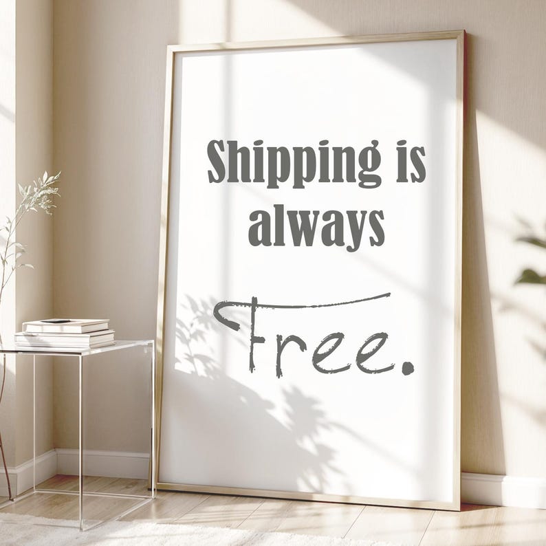 May include: A rectangular wall art print in a thin light-colored wooden frame. The white background features dark gray text that reads Shipping is always Free. The word Free is written in a stylized, handwritten script font with a horizontal line.