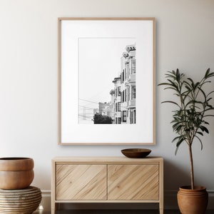 Photography print of pastel buildings in San Francisco with the Bay bridge in the bottom left background.  Black and white version. Shown framed for reference only.