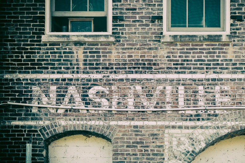 Nashville Photo Print has soft, muted colors of blue and gray.  Features the city's name on an old brick building.