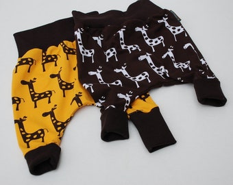 Könnte beinhalten: Zwei Paar Babyhosen mit Giraffenmuster. Ein Paar ist braun mit weißen Giraffen und das andere ist gelb mit braunen Giraffen.