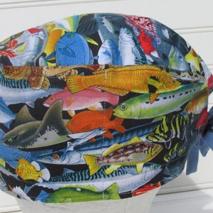 May include: A blue and black scrub hat with a colorful fish print. The hat has a blue tie.