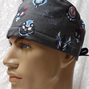 May include: A dark gray surgical scrub cap with a pattern of cartoon characters in blue, red, and black. The text "Solo Leveling" is printed on the side. The cap is tied in the back.