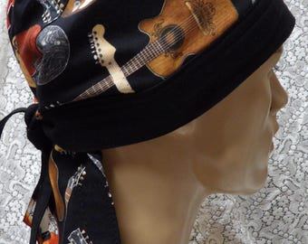 May include: Black head wrap featuring a repeating pattern of guitars in various styles and colors. The guitars include acoustic and electric models. The head wrap has a black band and ties.