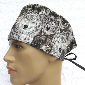 May include: A black and white patterned surgical scrub hat with a wolf print. The hat has a tie at the back.