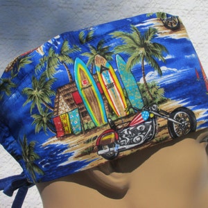 May include: Blue surgical scrub hat with a tropical beach scene featuring palm trees, surfboards, a hut, and a motorcycle. The hat has blue ties.