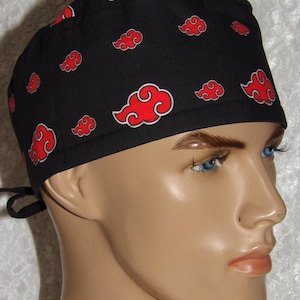 May include: Black surgical scrub cap with a repeating pattern of red clouds outlined in white. The cap is tied in the back and is worn by a mannequin. The cap is made of a soft, durable fabric.