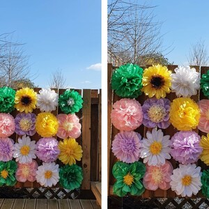 May include: A wall decorated with tissue paper flowers in various colors, including pink, yellow, green, and white. The flowers are arranged in a grid pattern and are attached to a wooden fence.