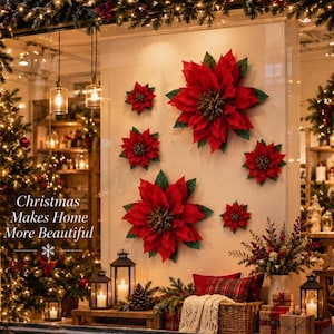 May include: A display of six large red poinsettia flowers with green leaves attached to a wall. The text "Christmas Makes Home More Beautiful" with a snowflake icon is visible on the left side of the glass window, overlooking a festive scene.