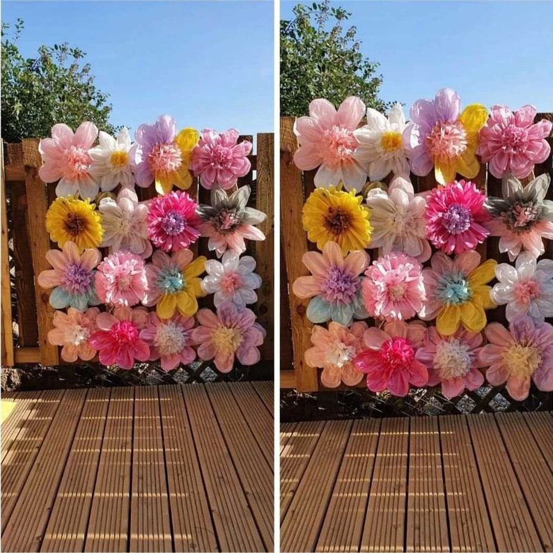 May include: A grid of twenty large, multi-layered paper flowers in various pastel and vibrant colours including pink, yellow, white, and blue. Each flower features a textured, ruffled centre and wide, rounded petals arranged in a square formation.