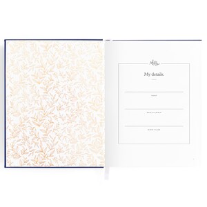 May include: A white journal with a navy blue cover and gold floral pattern. The inside page has a section for "My details." with lines for name, date of birth, and birth place.