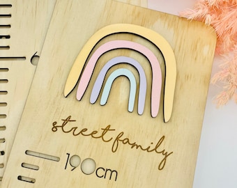 May include: Wooden height chart featuring a pastel rainbow design. The chart is engraved with the words "street family" and measures up to 190cm. The rainbow has yellow, pink, and blue arches.