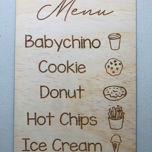 Puede incluir: Una tabla de men&uacute; de madera con esquinas redondeadas. La palabra "Menu" est&aacute; en la parte superior en cursiva. Debajo est&aacute;n las palabras "Babychino", "Cookie", "Donut", "Hot Chips" e "Ice Cream", cada una con una ilustraci&oacute;n correspondiente.