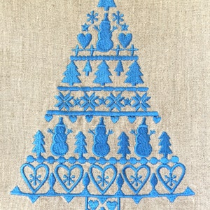 May include: Blue embroidered Christmas tree design on a linen fabric background. The design features snowmen, hearts, snowflakes, and pine trees.