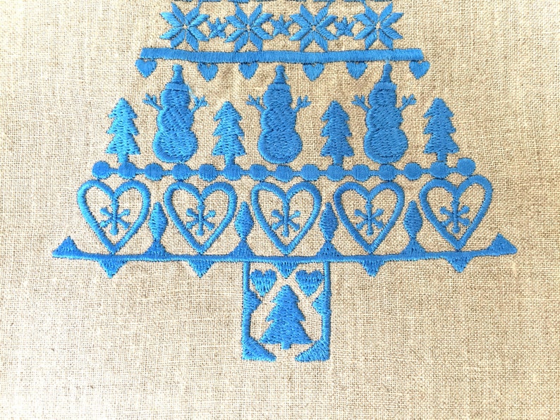 May include: Blue embroidered Christmas tree design on a beige linen fabric. The tree is decorated with snowmen, hearts, and snowflakes.