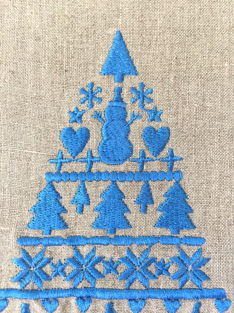 May include: Blue embroidered Christmas tree design on a beige linen fabric. The design features a snowman, snowflakes, hearts, and pine trees.
