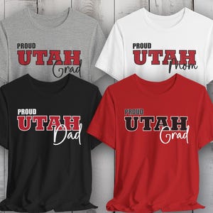 May include: Four t-shirts with the text "Proud Utah" in black and red lettering. The shirts are grey, white, black, and red. The text on the shirts says "Grad", "Mom", "Dad", and "Grad".