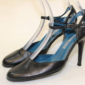 May include: Black leather ankle strap heels with a blue lining and a silver buckle. The heels are about 4 inches tall.