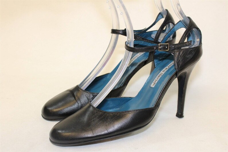 May include: Black leather ankle strap heels with a blue lining and a silver buckle. The heels are about 4 inches tall.