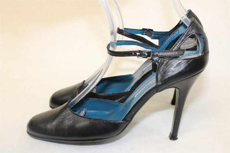 May include: Black leather high-heeled shoes with blue straps and a buckle closure.