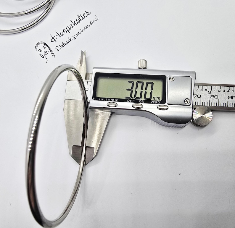 Może przedstawiać: Srebrny metalowy obręcz o średnicy 7,6 cm, zmierzony cyfrowym suwmiarką. Obręcz jest gładka i błyszcząca.