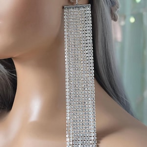 May include: Long silver dangle earrings with a cascade of clear rhinestones.