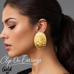 May include: A large, oval-shaped gold clip-on earring with a textured, hammered surface. The image includes the text "Clip-On Earrings" and "Gold or Silver" written in a script and sans-serif font, along with a small heart symbol.