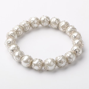 May include: A white pearl bracelet with silver filigree detailing. The bracelet is made of round pearls with a delicate, intricate design.