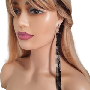 May include: Long black dangle earrings with a row of black rhinestones. The earrings are silver toned.