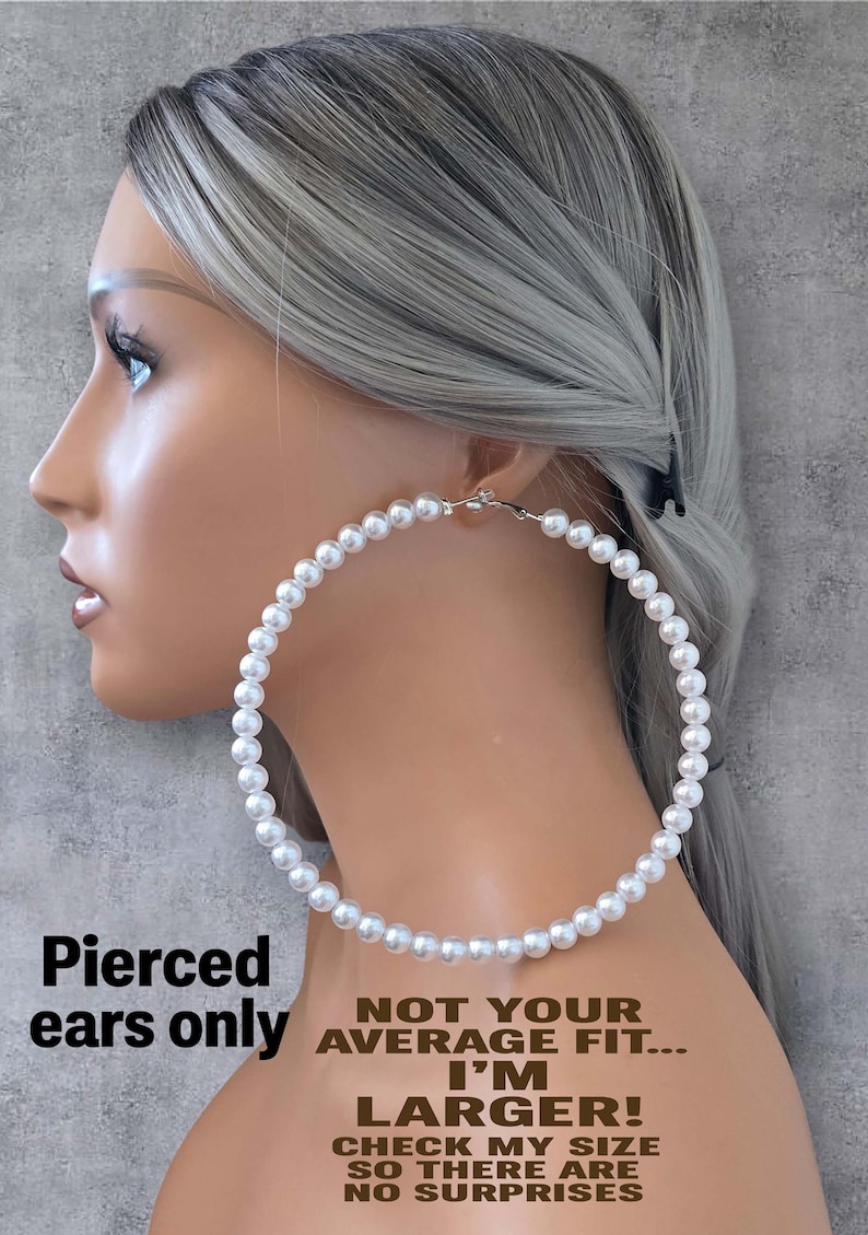 Pu&ograve; includere: Una persona con i capelli grigi indossa un grande orecchino a cerchio di perle. L'orecchino &egrave; fatto di perle bianche e ha una chiusura argentata. Il testo sull'immagine recita: "Pierced ears only. Not your average fit... I'm larger! Check my size so there are no surprises."