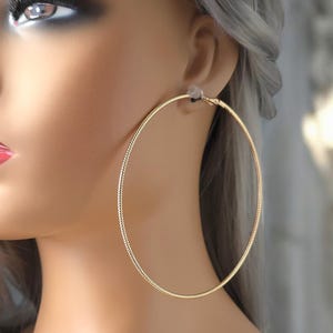 Op de afbeelding: Gouden creolen met een textuur. De oorbellen zijn groot en rond.