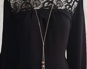 34" long Rose gold tone knotted lariat style necklace with natural lava beads & chain tassel detail