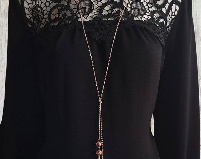 34" long Rose gold tone knotted lariat style necklace with natural lava beads & chain tassel detail