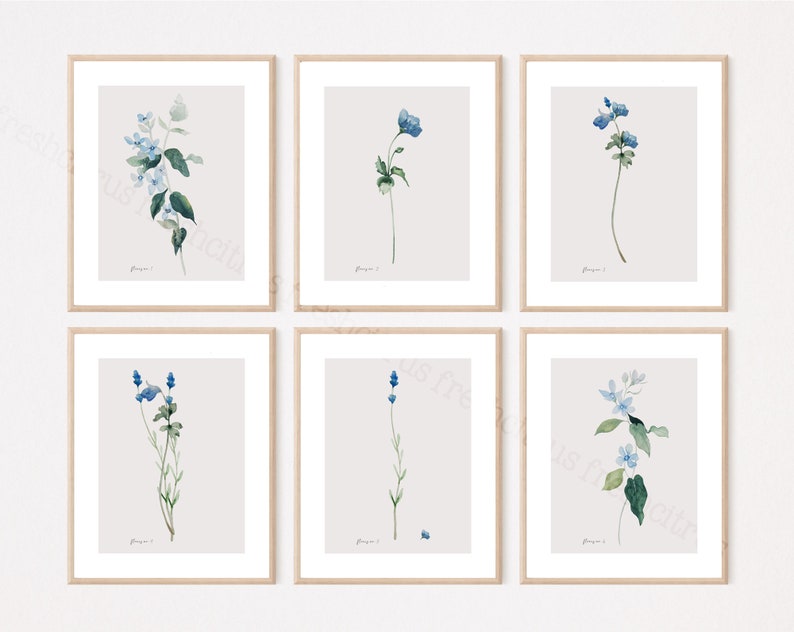 May include: Set of six botanical prints featuring watercolor illustrations of blue flowers with green leaves on a light gray background. Each print is framed in a light wood frame.