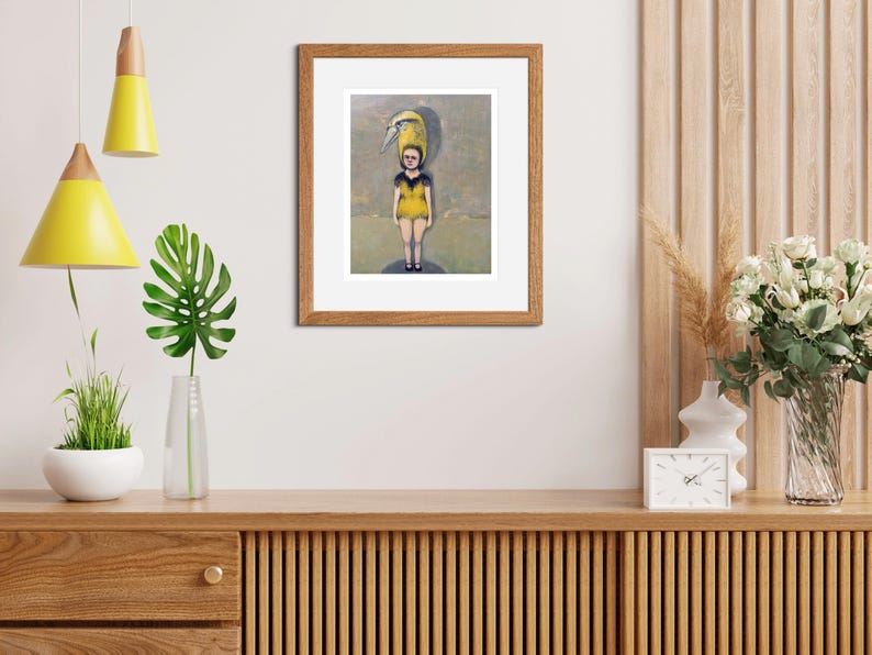 May include: A framed illustration of a young person wearing a yellow and black swimsuit with a yellow bird perched on their head. The background is a light blue and gray watercolor wash.
