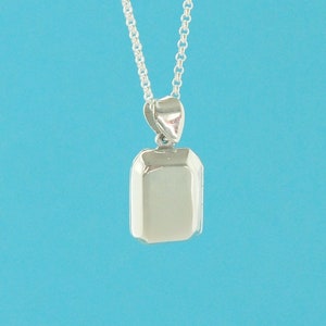 May include: A silver locket necklace with a rectangular pendant. The locket is closed and has a smooth, polished surface.