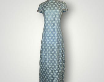 May include: A light blue vintage dress with a floral pattern. The dress has short sleeves and a high neckline with gold trim. The dress is floor-length and made of a delicate fabric, perfect for a special occasion.