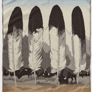 May include: A rectangular woven blanket featuring a graphic design of four large, upright feathers in black and white. Below the feathers, a herd of black bison silhouettes stands against a muted landscape. The top section shows a light blue sky.