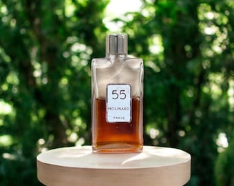 May include: A clear glass bottle of perfume with a silver cap. The bottle is filled with a brown liquid. The label on the bottle reads "55 Molinard Paris".