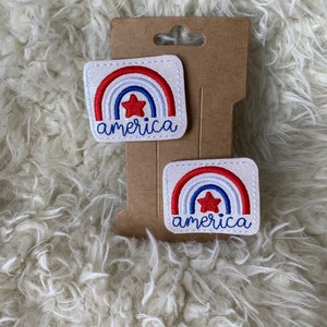 May include: Two white iron-on patches with red, white, and blue rainbow designs and a red star. The text "america" is embroidered in white on each patch.