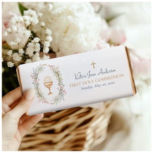 May include: White chocolate bar wrapper with a floral wreath design and a gold chalice. The text reads "Kateri Joan Anderson First Holy Communion Sunday, May 20, 20XX".