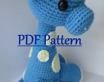 May include: A blue crocheted giraffe with white spots and a white crocheted horn. The giraffe is sitting on a white surface. PDF Pattern.